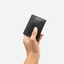 Une main tenant le porte-cartes en cuir noir de coter. Le logo signature Ace mis en avant.