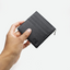 Porte-cartes Faubret noir en cuir grainé et Epi tenu dans une main.