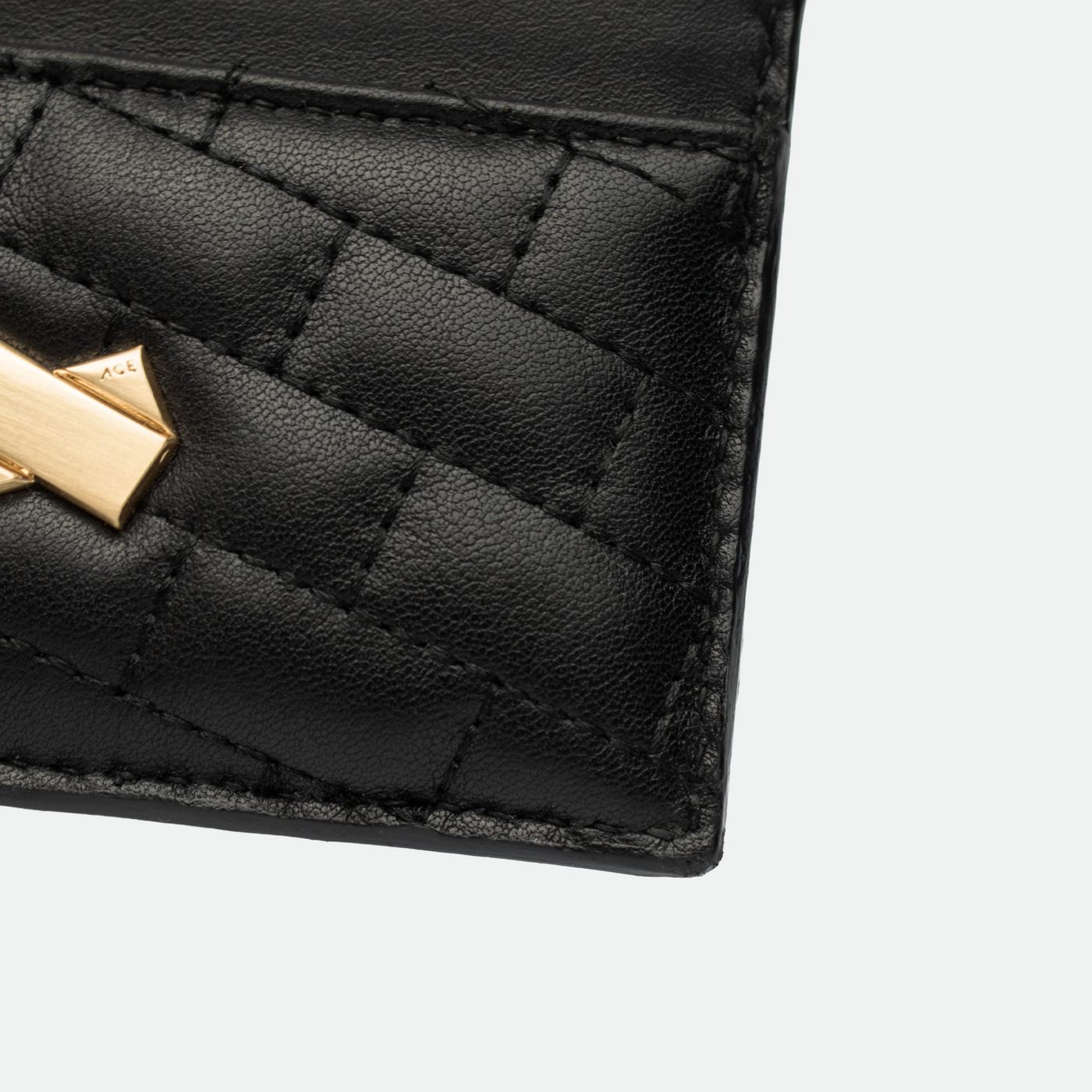 Gros plan sur la texture du cuir matelassé noir et signature Faubret doré du porte cartes femme