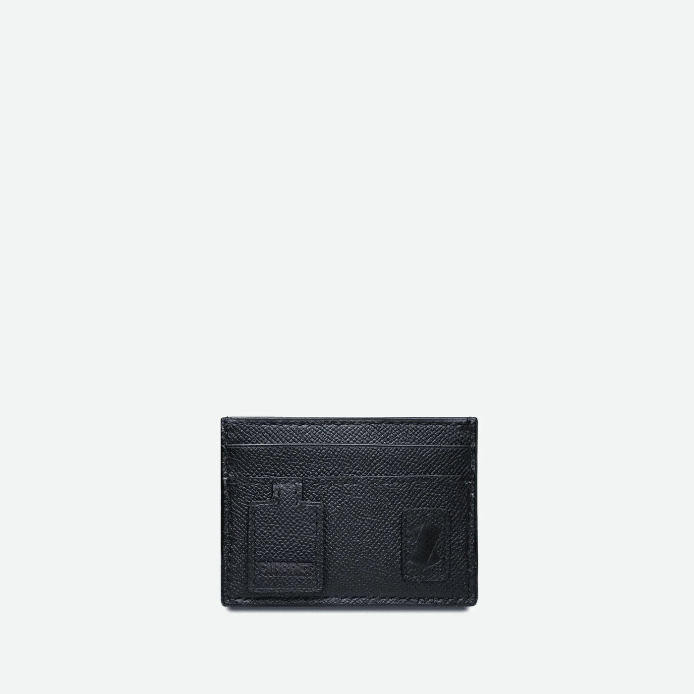 Porte-cartes en cuir grainé noir. Avec sur sa face avant le X iconique de la maison Faubret et une languette en cuir embossé Faubret.