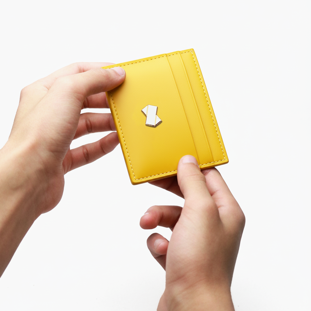 Porte-cartes jaune en cuir tenu en main, un accessoire compact et élégant pour le quotidien.