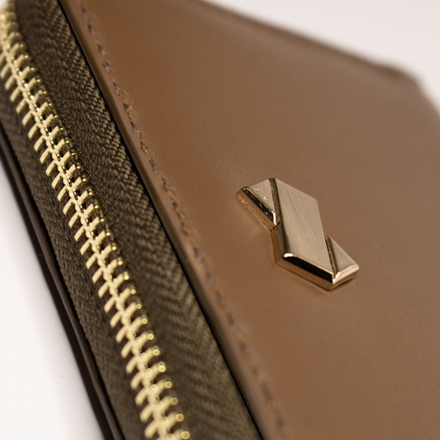 Gros plan sur le logo doré Faubret du porte monnaie et cartes femme en cuir marron.