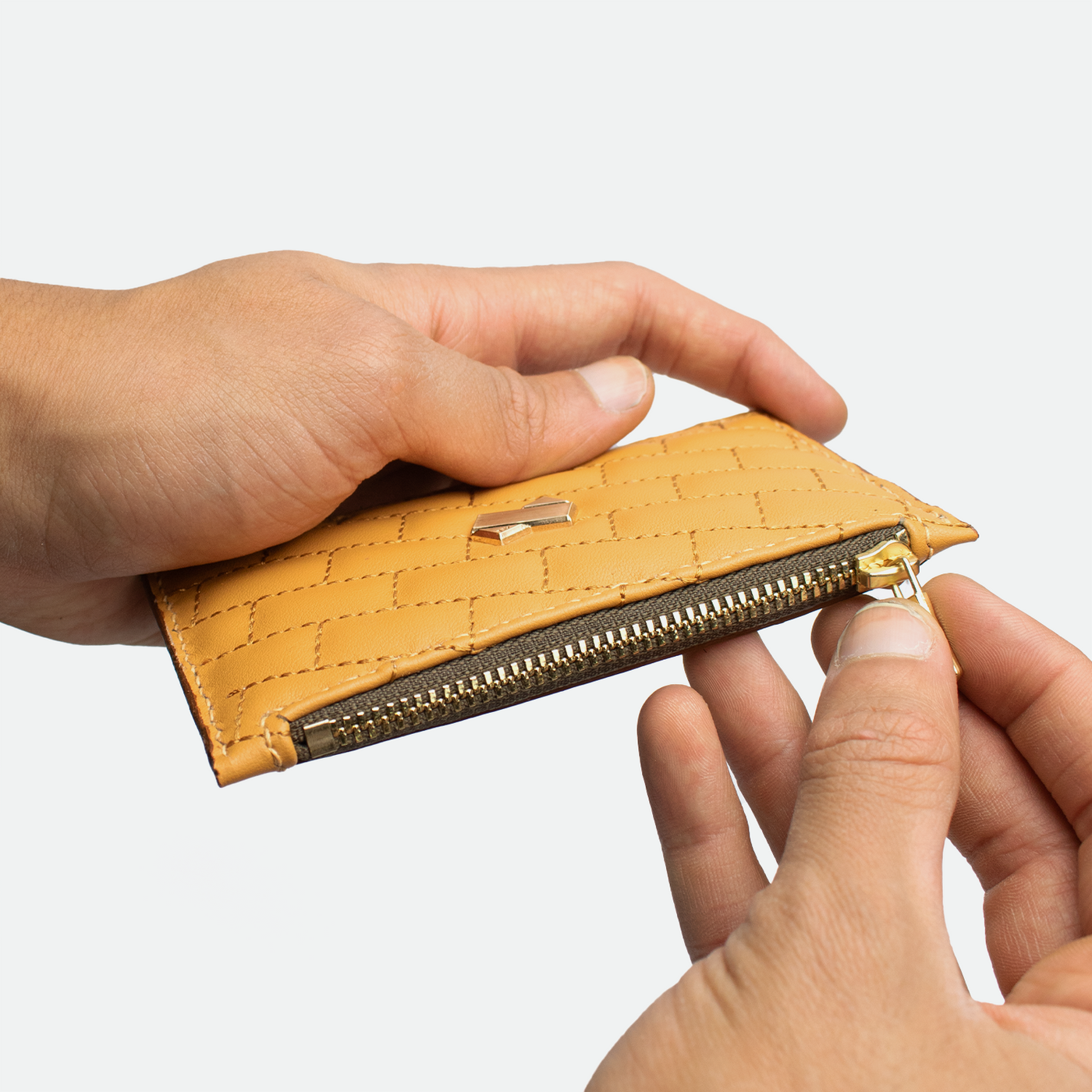 Porte monnaie cartes femme Faubret en cuir matelassé bicolore caramel marron, tenu en main, avec fermeture zippée dorée pour la monnaie.